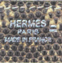 Hermès Varanus salvator lizard leather texture with "HERMES" branding – exotic skin detail.