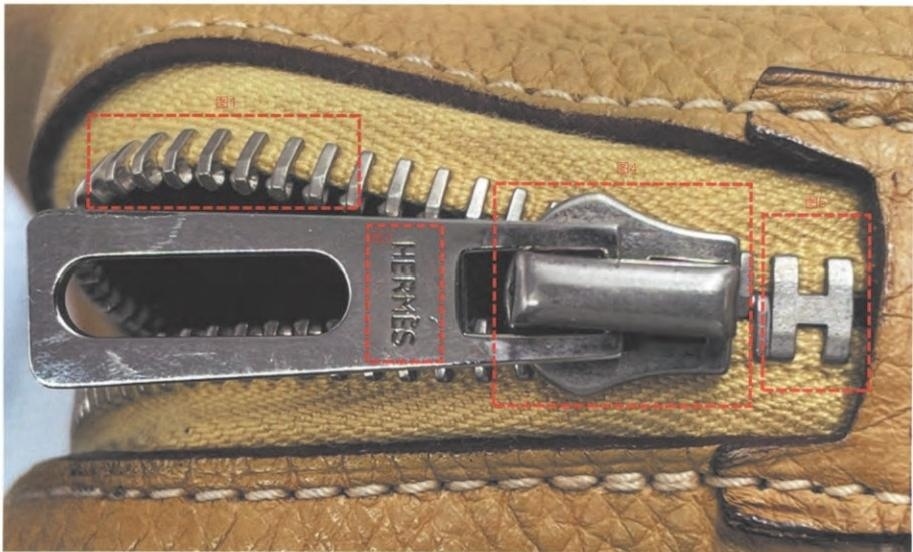 Hermès zipper pull engraved with "HERMS" and "H" – subtle branding on metal zipper.