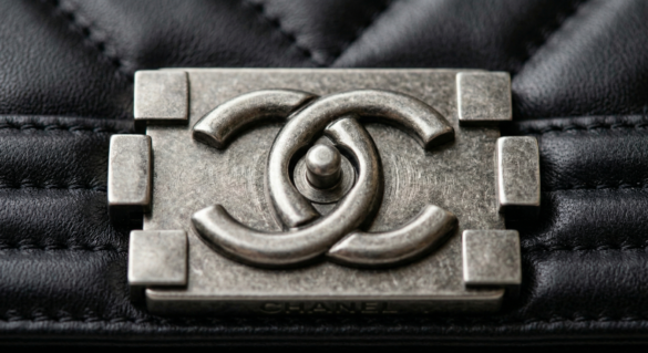 Macro close-up of authentic Chanel modern classic bags front CC lock hardware showing precise wire-drawing polishing marks.