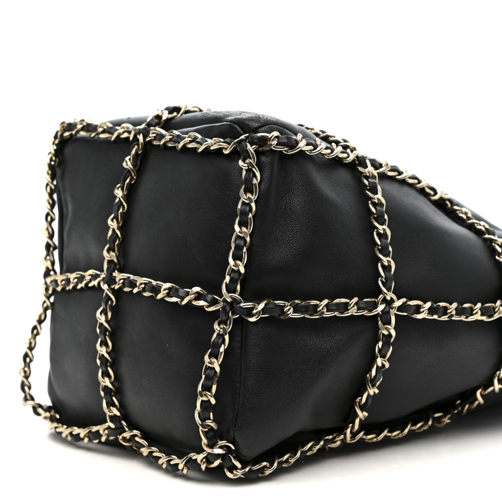 A detailed close-up of a black quilted leather hand bag with a unique exterior gold chain and black leather-interwoven mesh design, showcasing the intersection of comfort and style in iconic Chanel designs.