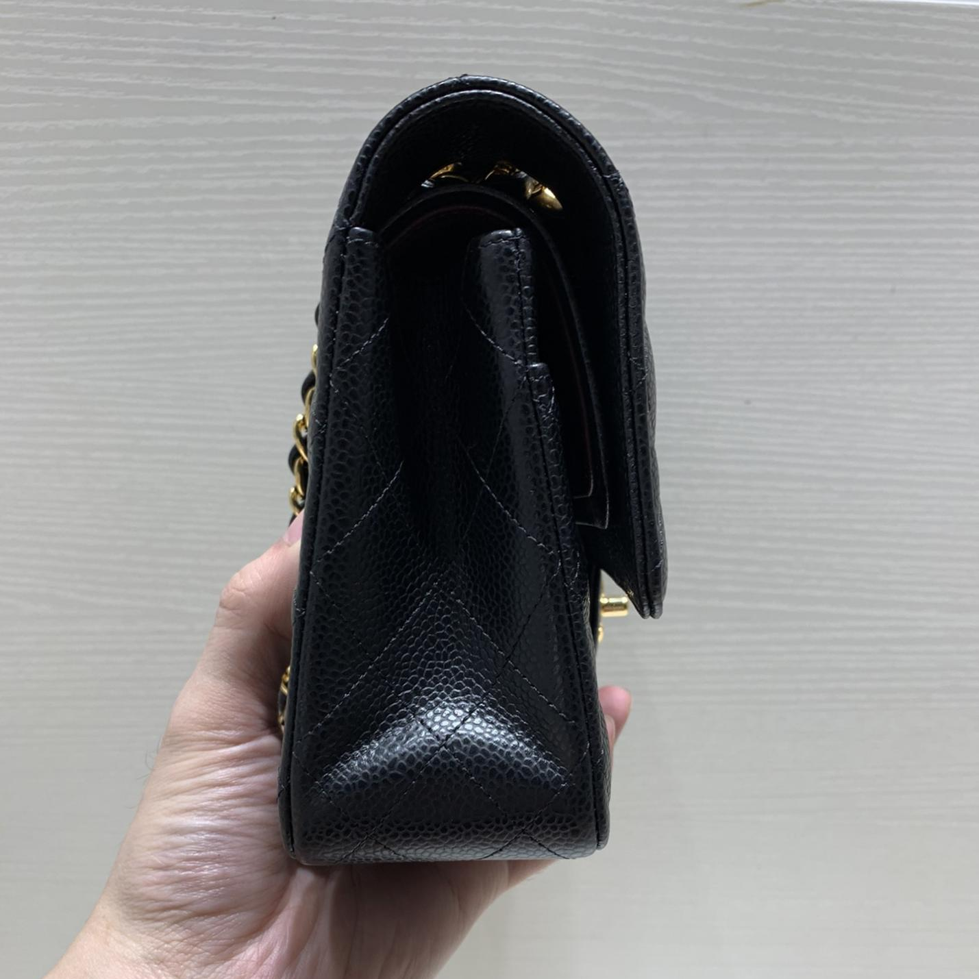 Side profile of a high-quality Chanel replica bag in black caviar leather, revealing its structured silhouette and burgundy interior edge, typical of the best Chanel replica bags.